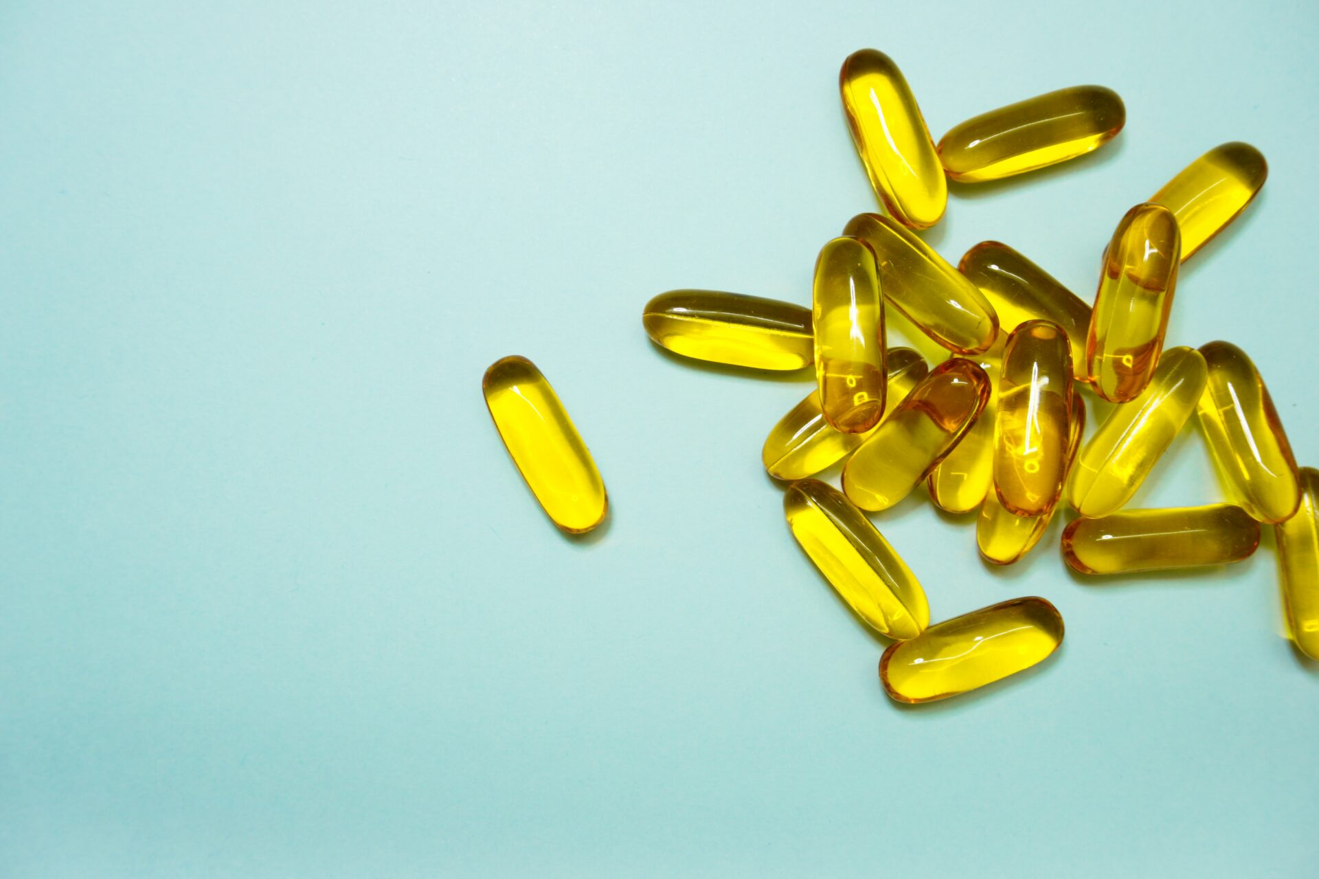 Pile of transparent yellow vitamin capsules on a blue background