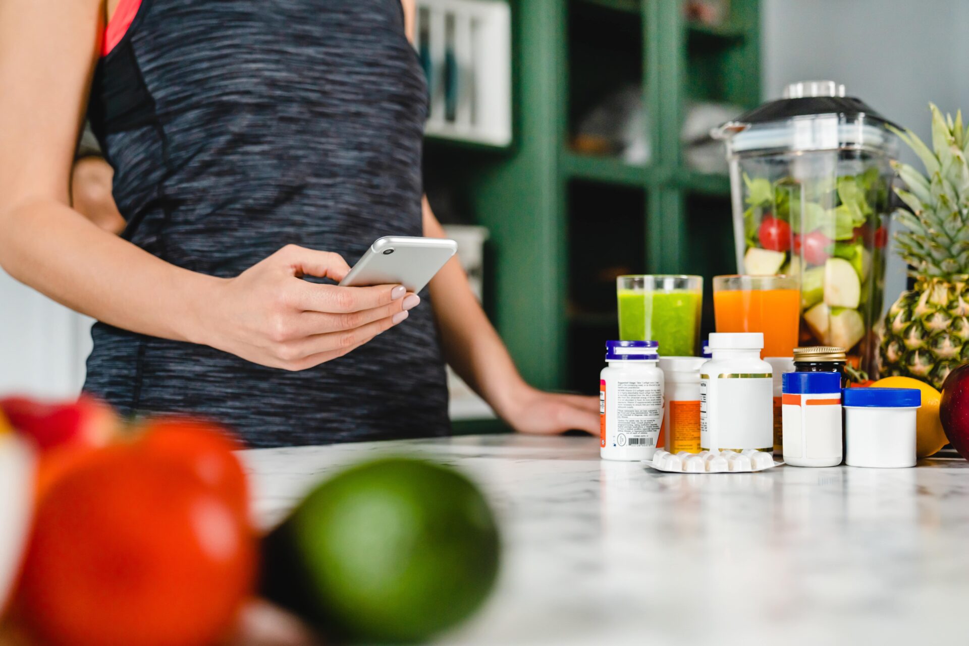young vegetarian woman standing in front of counter with smoothie and supplements for vegetarians