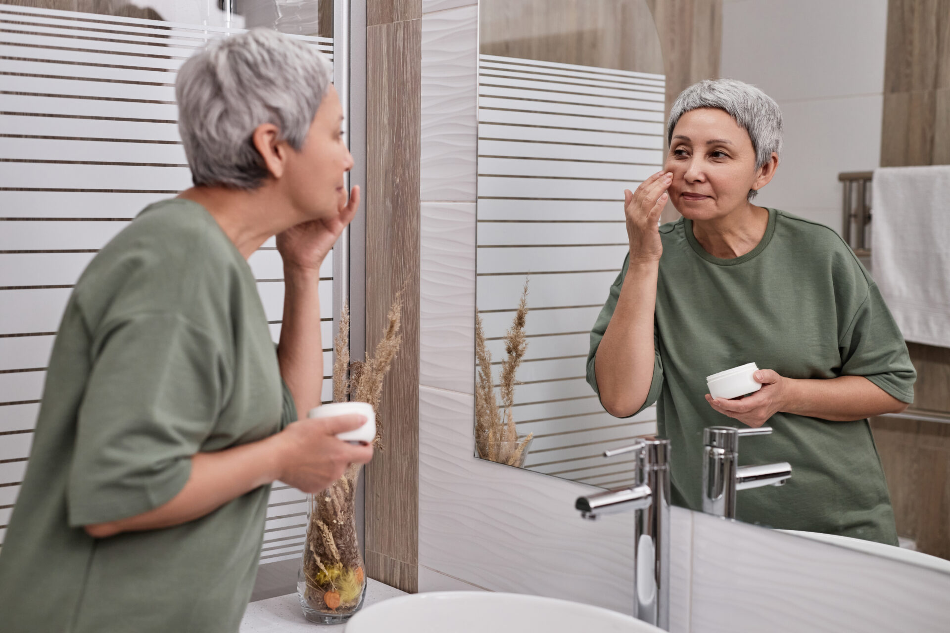 Old lady in washroom applying Cellular Rejuvenation cream.